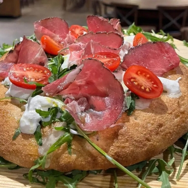 Pizza gourmet con stracciatella coppa stagionata e pomodorini